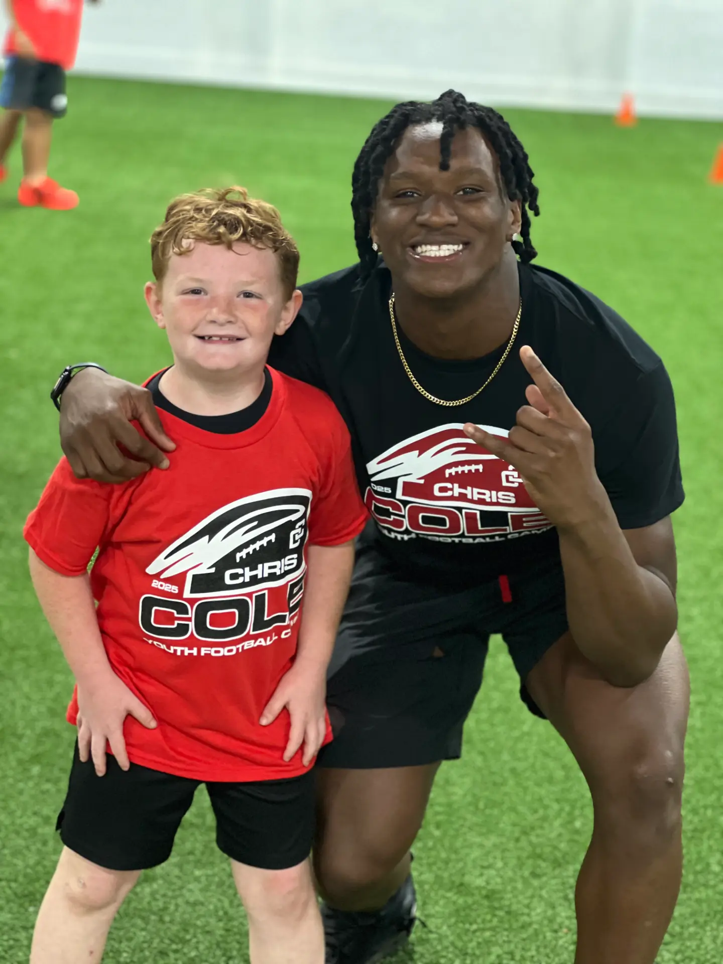 Chris Cole posing with a young camper on the turf