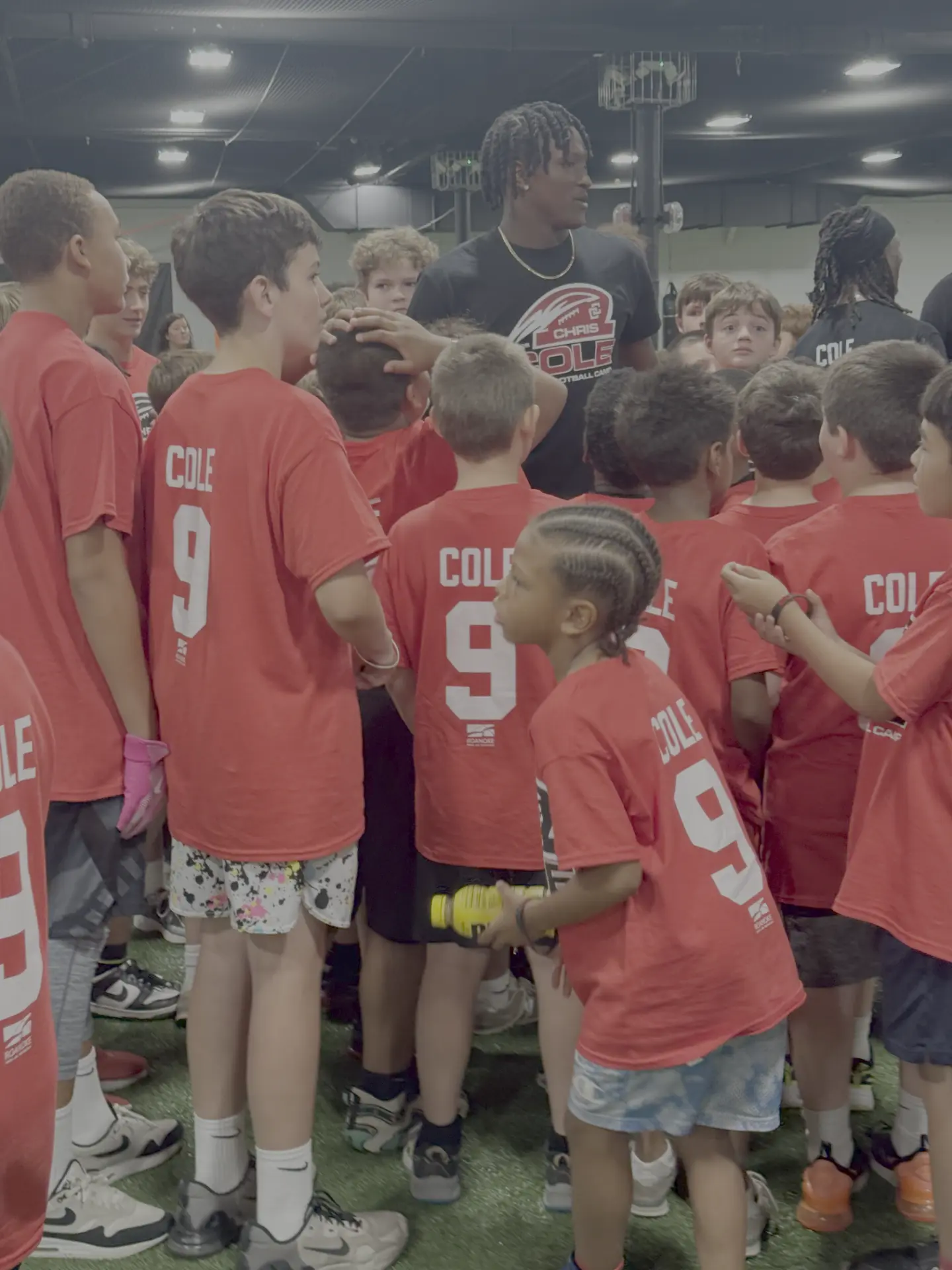 Chris Cole talking with a huddle of campers in COLE 9 shirts